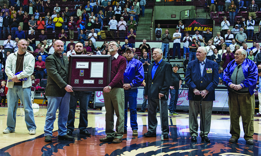 President Royce Engstrom and a group of veterans display the award naming UM a Purple Heart University. 